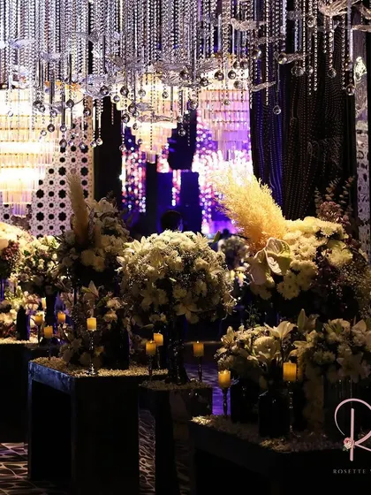 An entrance lined with white floral arrangements and candles, under a ceiling of hanging crystals. The design creates a sense of depth and luxury.