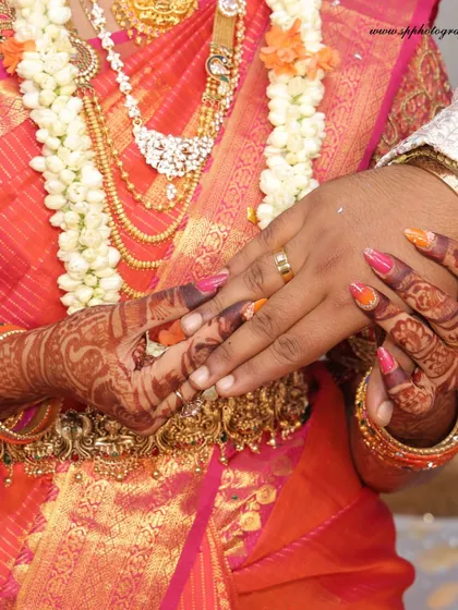 A close-up of the couple holding hands during their engagement. This shot beautifully captures the bride's Mehndi and the rings that signify their commitment.