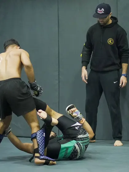 A coach watches over a live sparring session. Our coaches provide constant feedback and guidance, ensuring our fighters are always improving their technique and strategy.