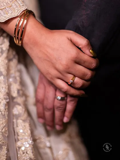 A close-up shot of the couple's hands, showcasing their newly exchanged engagement rings. A simple, powerful symbol of their commitment.