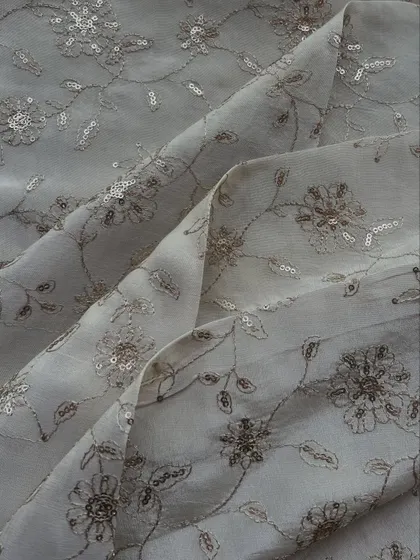 This embroidered tissue fabric features delicate floral embroidery with sequins on a sheer grey base, perfect for an elegant evening look.