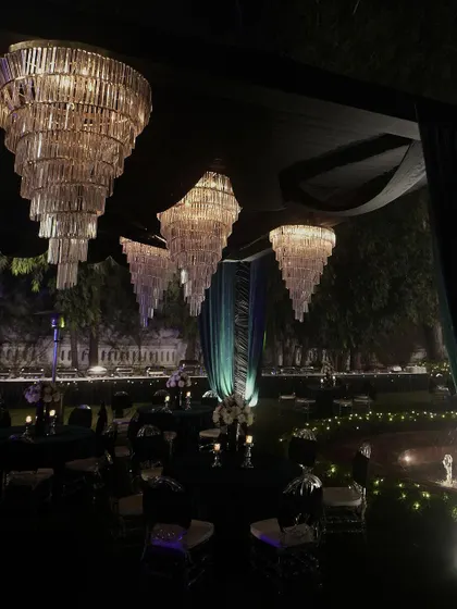 A breathtaking view of the Sangeet venue, with dozens of tiered chandeliers creating a forest of light under a canopy of dark teal fabric.