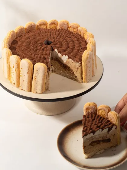 Our take on the classic Tiramisu. Ladyfingers soaked in espresso, layered with creamy mascarpone, and dusted with cocoa powder. Here it is with a slice taken out, showing the perfect layers.