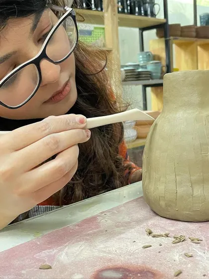 A student carefully carves lines into a vase, a simple yet effective way to add texture and a modern feel to their work.