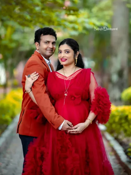 A classic pose for a beautiful couple. Dressed in a stunning red gown, this mom-to-be and her partner are ready to welcome their little bundle of joy.
