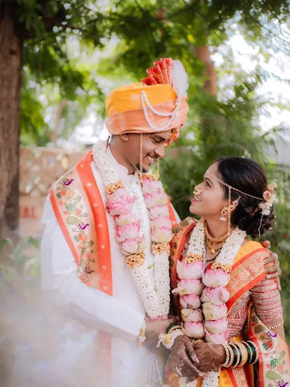 The couple sharing a loving gaze, surrounded by beautiful lotus 'varmalas', a perfect capture of wedding day romance.