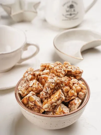 My peanut chikki served in a simple bowl, ready for you to enjoy. I focus on the taste and quality, ensuring each piece delivers that satisfying, nostalgic crunch.
