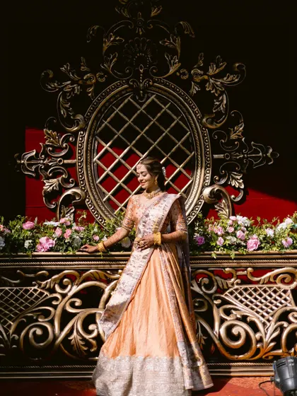 The bride against a grand, ornate backdrop. Her traditional outfit and glowing makeup make her look like royalty.