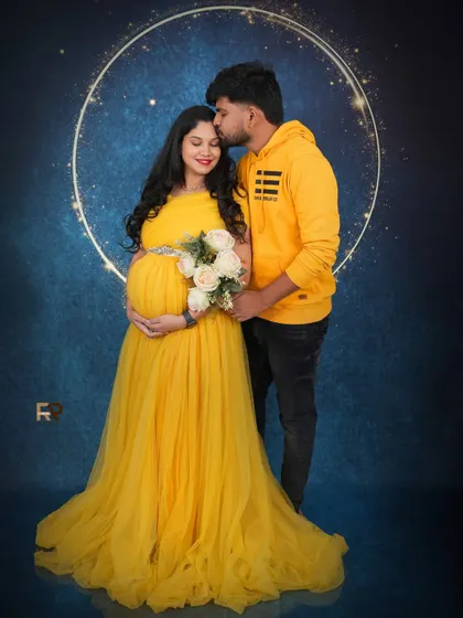 A celestial love story. The couple stands before a glowing moon prop, sharing a tender kiss on the forehead. It's a perfect blend of romance and magic.