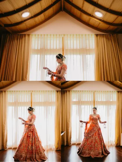 A symmetrically framed shot of a bride in her orange lehenga, standing before a large window, with reflections creating a beautiful, layered effect.