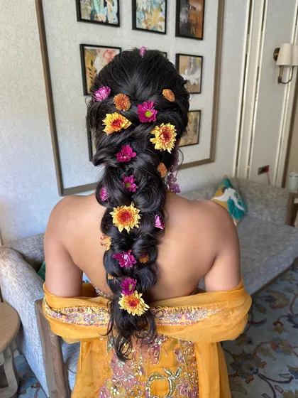 There's nothing like fresh flowers to bring a hairstyle to life. This voluminous, messy braid for a Haldi ceremony is adorned with vibrant, colorful flowers, creating a look that is joyful, festive, and perfectly in tune with the celebration.