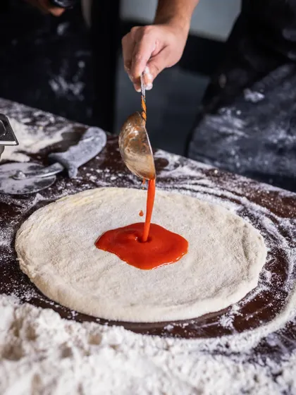 Pizza perfection in the making. The process of building a pizza is a ritual, from the dough to the sauce to the toppings, each step done with care.