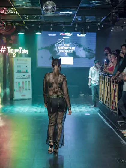 A shot from behind, showcasing the sheer back of the outfit and the model's confident exit from the runway.