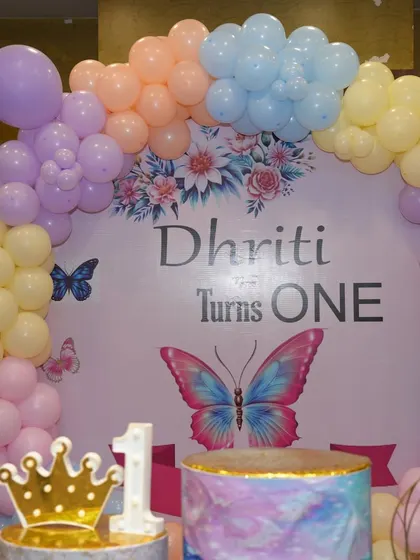 A close-up of the 'Dhruti Turns One' butterfly-themed backdrop.
