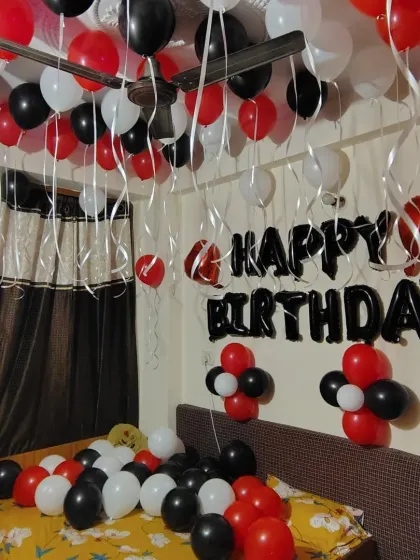 A simple birthday room decoration with red, black, and white balloons. The setup includes 'Happy Birthday' foil letters on the wall.