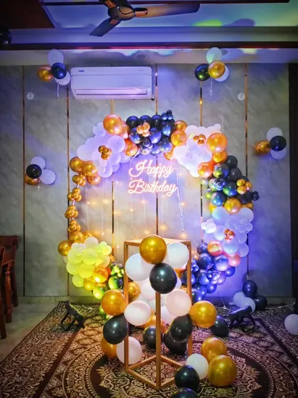 Another view of the black, white, and gold balloon arch, showing how it looks with different lighting. The neon sign and fairy lights add a beautiful glow.
