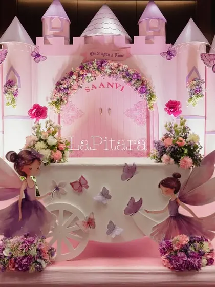 The main stage for the enchanted princess party, featuring a castle backdrop, fairy cutouts, and a whimsical carriage.