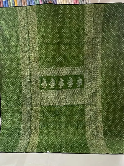 A two-in-one memory quilt made from two different green and orange sarees. This reversible design allows for versatility while preserving the beauty of both cherished garments.
