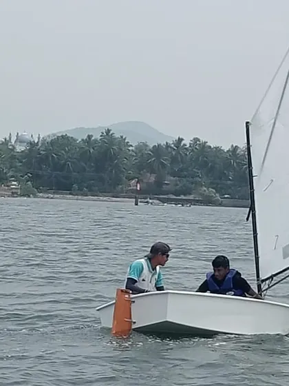 An instructor provides guidance to a young sailor as they navigate the waters of Karwar.