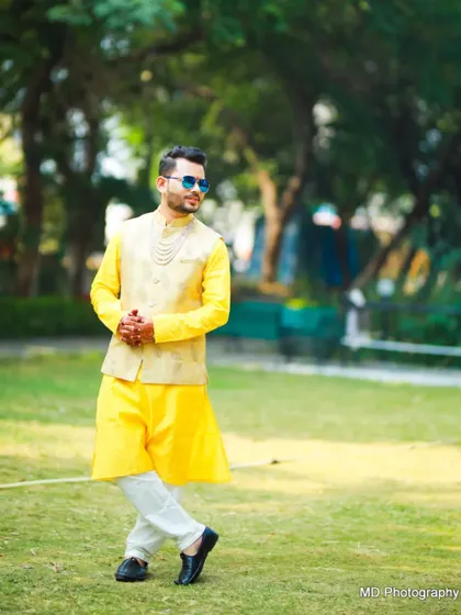 A stylish Haldi look. The groom pairs a bright yellow kurta with a beige waistcoat and cool sunglasses for a fun, modern vibe.