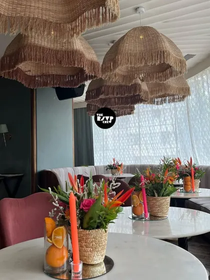 The table settings for the 40th birthday party, with beautiful wicker lampshades overhead and fresh floral centerpieces with citrus accents.