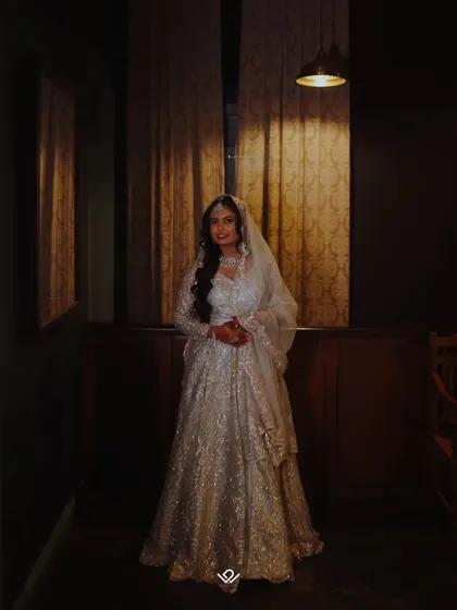 A moody, full-length portrait of a bride in her reception gown, using shadows and light for a dramatic effect.