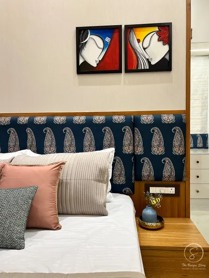 A detailed shot of the bedside, highlighting the rich texture of the paisley headboard, the simple wooden nightstand, and the modern art above. This juxtaposition of traditional and contemporary is a key feature of our style.