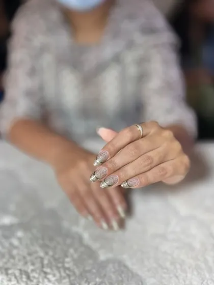 A glittery gold French tip on a nude base. This is a glamorous and festive look perfect for any party.