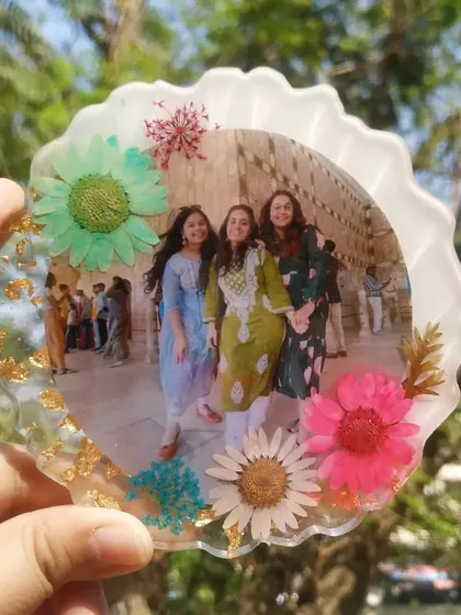 A clear shot of the floral friendship frame in natural light. The vibrant colors of the pressed flowers really stand out against the white resin base.