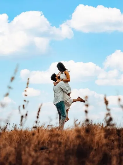 A classic "lift" pose against a bright blue sky, capturing a moment of pure joy and freedom. This kind of shot adds a dynamic and celebratory feel to your pre-wedding album.