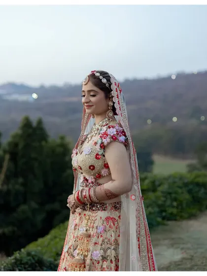 A beautiful bridal portrait with a scenic mountain backdrop. The bride's floral lehenga complements the natural setting, creating a stunning image from a destination wedding.