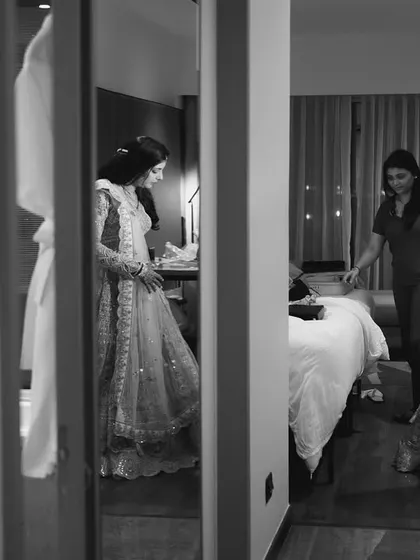 A candid black and white shot of the bride getting help with her outfit.