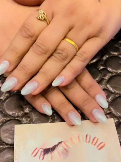 A simple and elegant set of almond-shaped nails with a pearlescent, shimmery white finish. This look is clean, modern, and sophisticated.