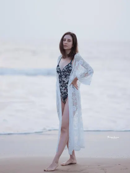 A classic beach fashion portrait. The model's pose is confident and the soft, even lighting is ideal for showcasing both the person and the clothing.