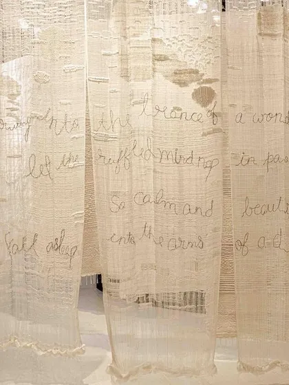 A detail of the 'Sleep Sense' installation, where poetry is hand-stitched onto translucent fabric. This element adds a layer of narrative and intimacy to the piece.