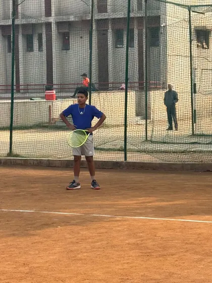 A young player stands ready on the court, racquet in hand. This posture of readiness is the first step to winning any point.
