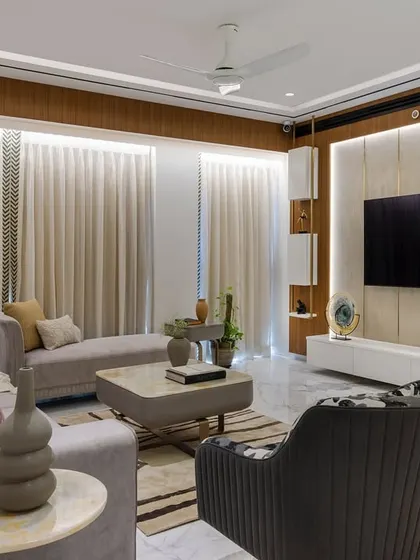 A wide shot of the open living and dining space, showcasing the fluted ceiling border, pastel sofas, and the exotic marble dining wall. The design combines classic elegance with modern luxury.