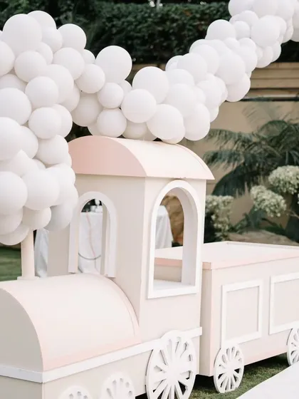 A charming pastel train prop with a "steam" of white balloons, creating a playful and imaginative photo opportunity for the birthday child and friends.