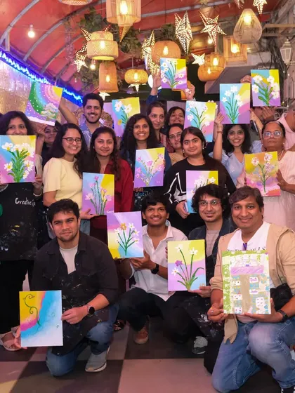 The energy in our group workshops is just incredible. Look at all these happy artists proudly holding up the floral paintings they created during a fun-filled session.
