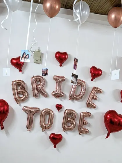 A close-up of the 'Bride to be' setup, showing personal photos of the bride-to-be hanging from the ceiling balloons for a personalized touch.