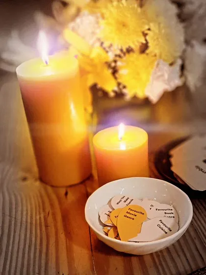 A close-up of the details from a Bumble event reading. The candles provide warmth, while the small cards in the bowl act as icebreakers, inviting guests to engage.