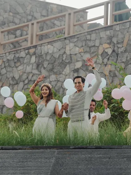 A grand, celebratory entrance, waving to their loved ones, with balloons adding to the festive atmosphere.