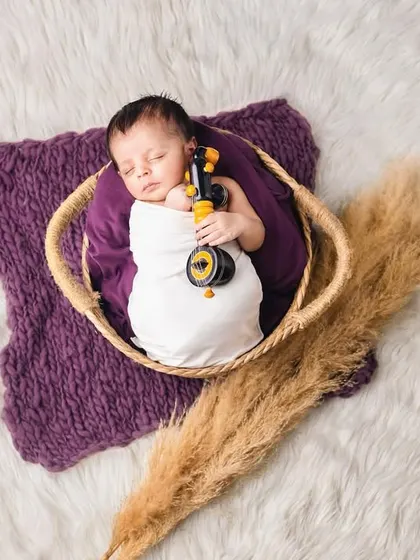 This little one is holding a tiny violin, ready for a symphony of dreams. The simple props and soft textures keep the focus on the baby.