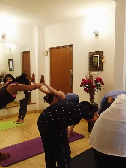 A group of students practicing a forward fold variation together. This pose is excellent for stretching the hamstrings and releasing tension in the back.