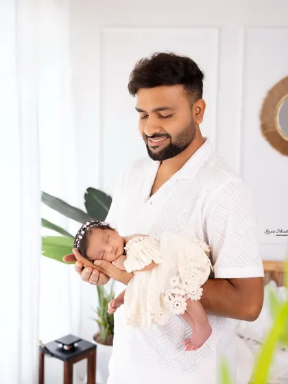 A proud father holds his tiny newborn, a beautiful portrait showcasing their immediate bond.