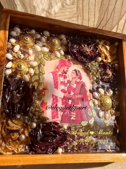 A close-up of a teakwood frame preserving a client's wedding varmala and kaleera. The details show the care and artistry that go into each piece.