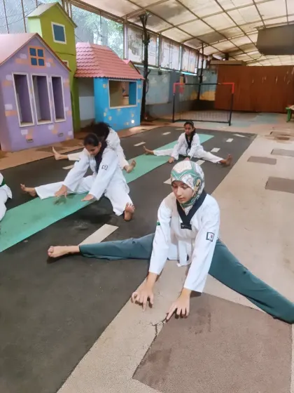 Students hold a deep stretch, working on their splits. This level of flexibility is essential for executing high kicks and advanced techniques.