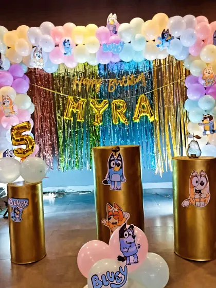 For this 5th birthday, I designed a party around the popular cartoon Bluey. The decor features a pastel balloon arch, a shimmering backdrop, and character cutouts on golden pedestals, creating a fun and colorful atmosphere.