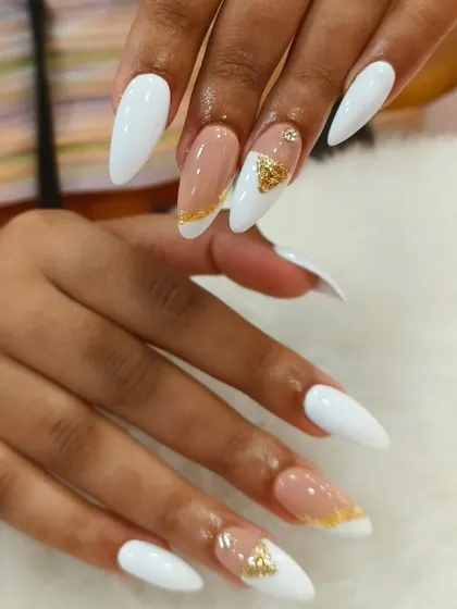 Clean lines and luxurious details define this look. Crisp white stiletto extensions provide the perfect canvas for a negative space design accented with shimmering gold foil. This style is a testament to our precision and minimalist glamour.