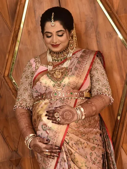 A graceful portrait of a mom-to-be. Her hands, decorated with intricate mehendi, gently cradle her baby bump, showcasing the beautiful henna work.